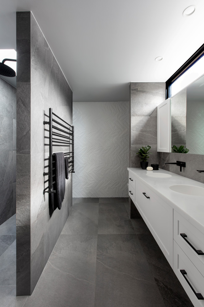 This is an example of a contemporary master bathroom in Melbourne with recessed-panel cabinets, white cabinets, a double shower, a one-piece toilet, white tile, cement tile, white walls, porcelain floors, an integrated sink, solid surface benchtops, grey floor, an open shower, white benchtops, a double vanity and a floating vanity.