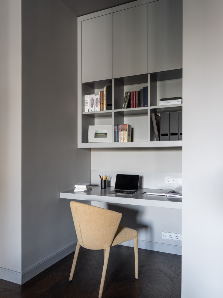 This is an example of a small contemporary study room in Moscow with grey walls, dark hardwood floors, a ribbon fireplace, a tile fireplace surround, a built-in desk and brown floor.