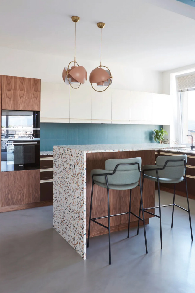 Example of a mid-sized u-shaped ceramic tile and beige floor eat-in kitchen design in Los Angeles with an integrated sink, flat-panel cabinets, white cabinets, terrazzo countertops, blue backsplash, ceramic backsplash, black appliances, an island and white countertops