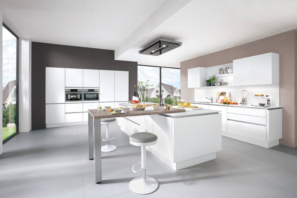 Design ideas for a large contemporary u-shaped open plan kitchen in Hamburg with an integrated sink, flat-panel cabinets, beige cabinets, wood benchtops, beige splashback, glass sheet splashback, stainless steel appliances, cement tiles, a peninsula and grey floor.