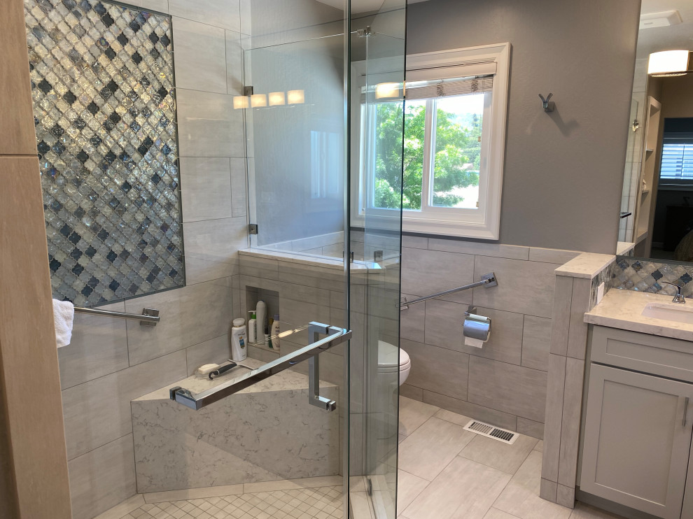 Photo of a mid-sized transitional master bathroom in San Francisco with shaker cabinets, a corner shower, a two-piece toilet, gray tile, porcelain tile, grey walls, porcelain floors, an undermount sink, engineered quartz benchtops, grey floor, a hinged shower door, multi-coloured benchtops, a shower seat, a double vanity and a built-in vanity.