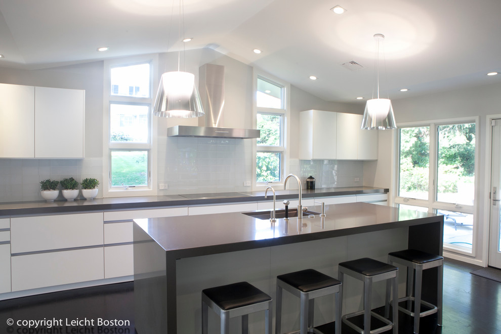 This is an example of a large contemporary single-wall eat-in kitchen in Boston with an undermount sink, flat-panel cabinets, dark wood cabinets, white splashback, subway tile splashback, stainless steel appliances, dark hardwood floors and with island.