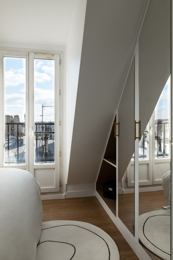 Design ideas for a small contemporary loft-style bedroom in Paris with white walls and medium hardwood floors.