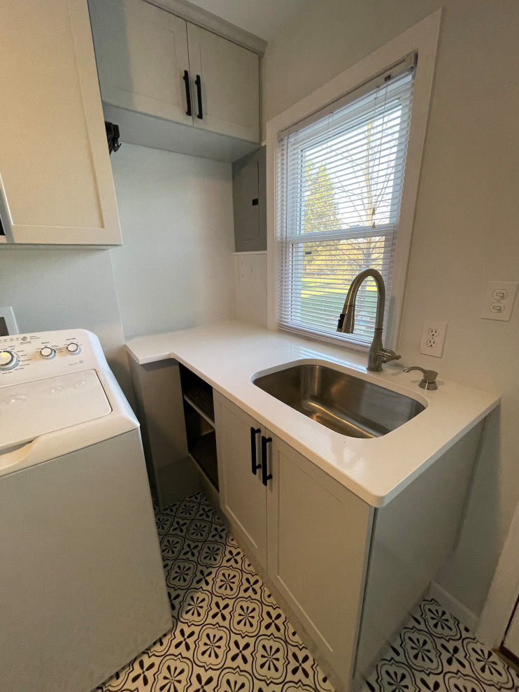 This is an example of a small transitional l-shaped utility room in Detroit with an undermount sink, shaker cabinets, grey cabinets, quartz benchtops, grey walls, ceramic floors, a side-by-side washer and dryer, white floor and white benchtop.