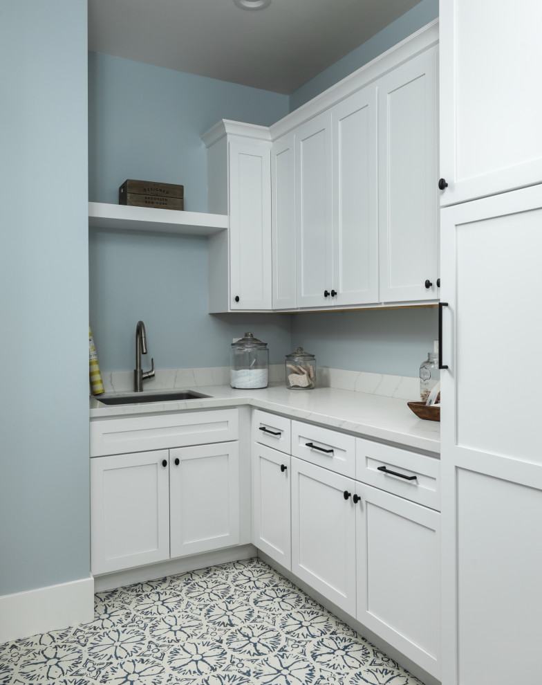 Inredning av ett modernt stort grå u-format grått grovkök, med en undermonterad diskho, skåp i shakerstil, vita skåp, bänkskiva i kvarts, grått stänkskydd, blå väggar, klinkergolv i keramik, en tvättmaskin och torktumlare bredvid varandra och blått golv