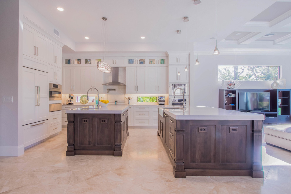 Huge transitional l-shaped porcelain tile and beige floor open concept kitchen photo with a farmhouse sink, shaker cabinets, white cabinets, quartz countertops, white backsplash, porcelain backsplash, stainless steel appliances and two islands