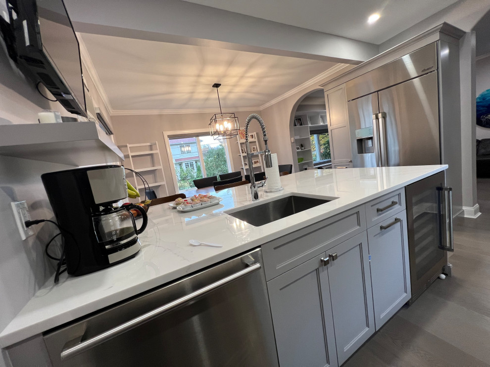 Bild på ett mellanstort vintage flerfärgad flerfärgat kök, med en undermonterad diskho, luckor med infälld panel, grå skåp, bänkskiva i kvarts, flerfärgad stänkskydd, stänkskydd i porslinskakel, rostfria vitvaror, ljust trägolv, en köksö och grått golv
