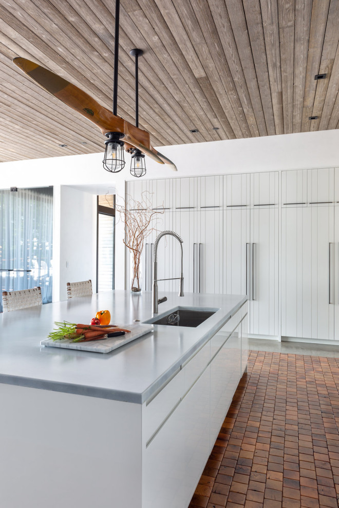 Photo of a medium sized rustic u-shaped kitchen/diner in Los Angeles with a submerged sink, louvered cabinets, white cabinets, composite countertops, stainless steel appliances, terracotta flooring, an island, orange floors, white worktops and a wood ceiling.
