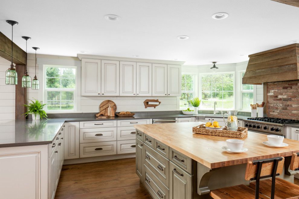 This is an example of a mid-sized country u-shaped open plan kitchen in Seattle with an undermount sink, raised-panel cabinets, white cabinets, quartz benchtops, white splashback, shiplap splashback, stainless steel appliances, medium hardwood floors, with island, brown floor and grey benchtop.
