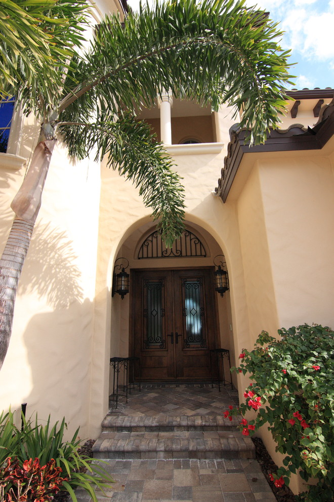 Large mediterranean front door in Orlando with beige walls, ceramic floors, a double front door and a medium wood front door.