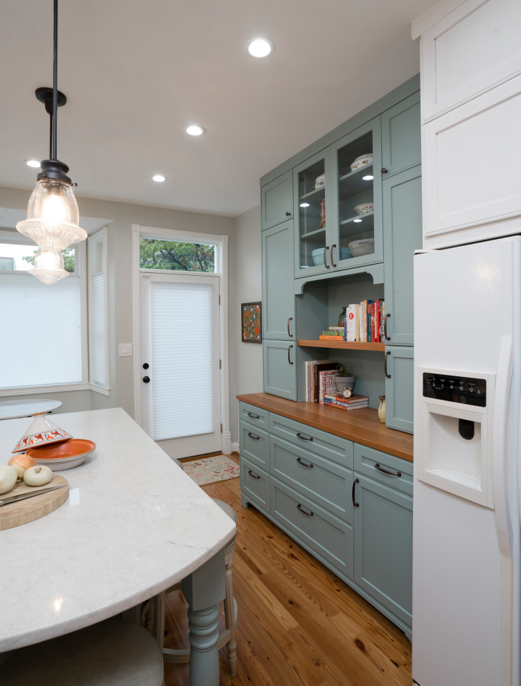 This is an example of a mid-sized traditional galley separate kitchen in DC Metro with a double-bowl sink, recessed-panel cabinets, green cabinets, quartz benchtops, green splashback, ceramic splashback, white appliances, medium hardwood floors, with island, brown floor and white benchtop.