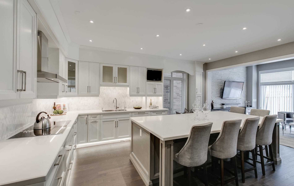 Example of a huge transitional u-shaped dark wood floor and brown floor eat-in kitchen design in Toronto with a double-bowl sink, recessed-panel cabinets, white cabinets, marble countertops, gray backsplash, stone tile backsplash, stainless steel appliances, an island and white countertops