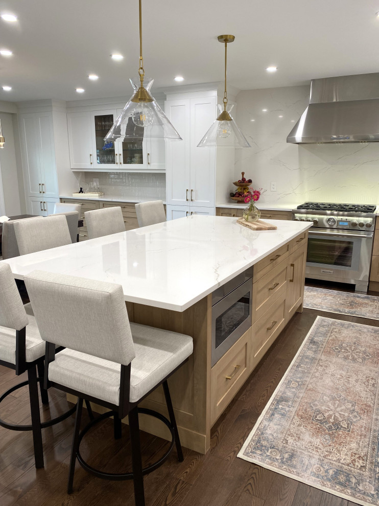 Example of a mid-sized transitional l-shaped medium tone wood floor and brown floor eat-in kitchen design in Toronto with an undermount sink, shaker cabinets, white cabinets, quartz countertops, white backsplash, quartz backsplash, stainless steel appliances, an island and white countertops