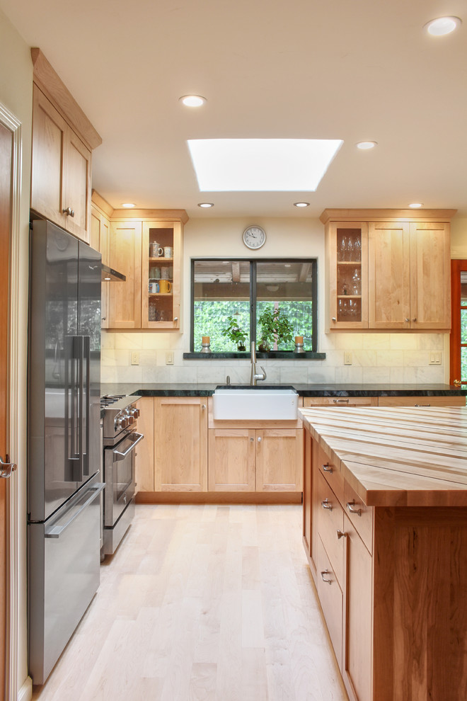 Inspiration for a mid-sized transitional l-shaped light wood floor and brown floor eat-in kitchen remodel with a farmhouse sink, shaker cabinets, light wood cabinets, soapstone countertops, white backsplash, marble backsplash, stainless steel appliances and an island