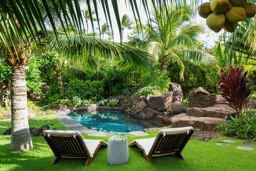 Large tropical backyard partial sun garden in Hawaii with natural stone pavers for summer.