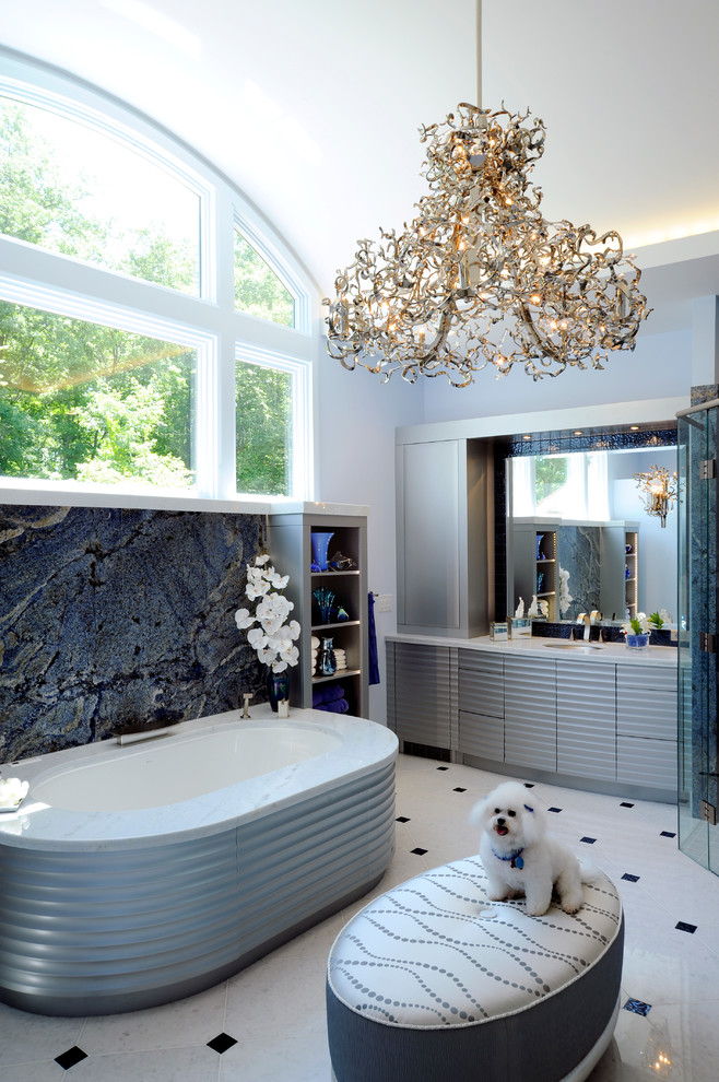 This is an example of a mid-sized contemporary master bathroom in Columbus with grey cabinets, an undermount tub, blue tile, stone slab, a corner shower, blue walls, porcelain floors, an undermount sink, solid surface benchtops, white floor, a hinged shower door and flat-panel cabinets.