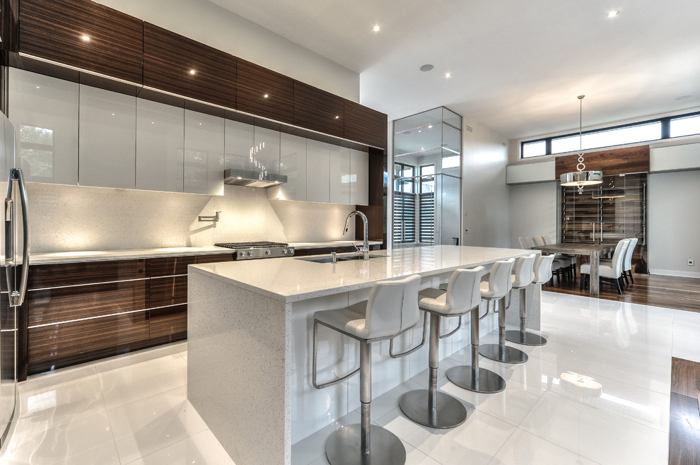 Large contemporary u-shaped open plan kitchen in Montreal with glass-front cabinets, dark wood cabinets, quartz benchtops, stainless steel appliances and with island.