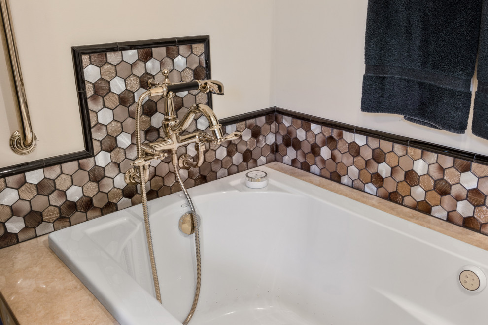 Photo of a large traditional master bathroom in Milwaukee with brown walls, dark hardwood floors, brown floor, raised-panel cabinets, white cabinets, a drop-in tub, a corner shower, a two-piece toilet, multi-coloured tile, glass tile, an undermount sink, engineered quartz benchtops, a hinged shower door and beige benchtops.