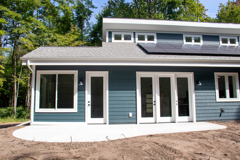 Cette image montre une façade de maison bleue minimaliste en bardage à clin de taille moyenne et à niveaux décalés avec un revêtement en vinyle, un toit en appentis, un toit en shingle et un toit noir.