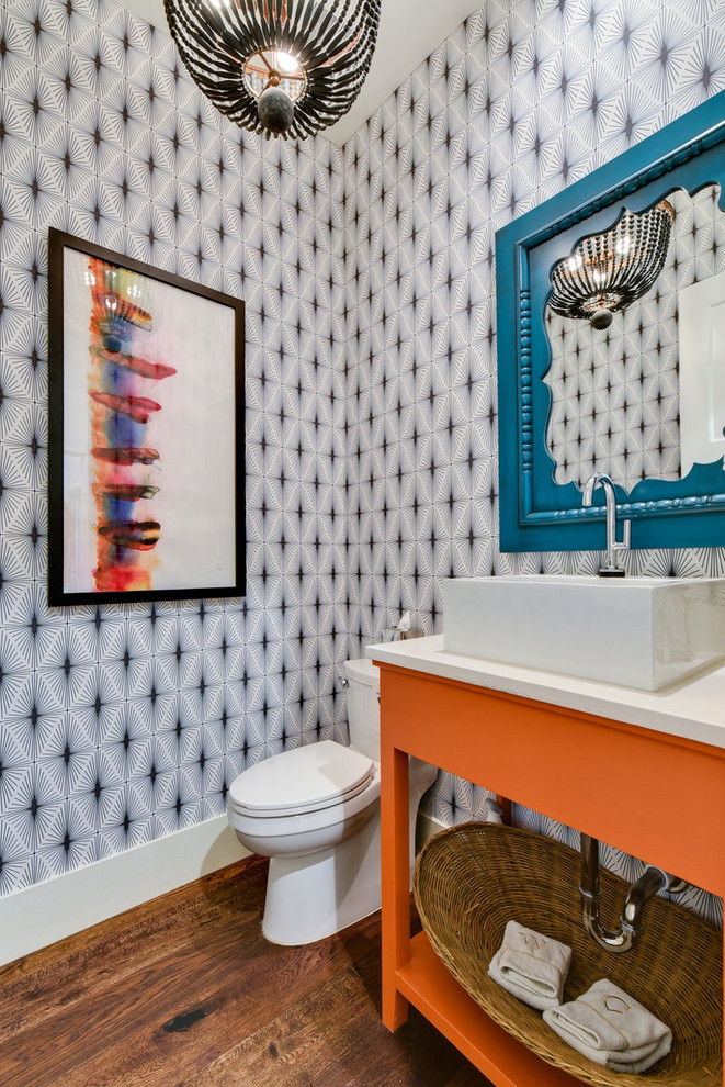 Photo of a contemporary powder room in Austin with furniture-like cabinets, orange cabinets, multi-coloured walls, dark hardwood floors, a vessel sink, brown floor and white benchtops.