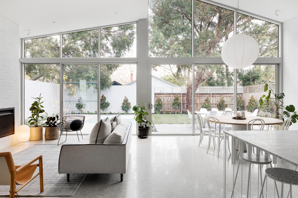 This is an example of a large contemporary open concept living room in Melbourne with concrete floors, a standard fireplace and a brick fireplace surround.