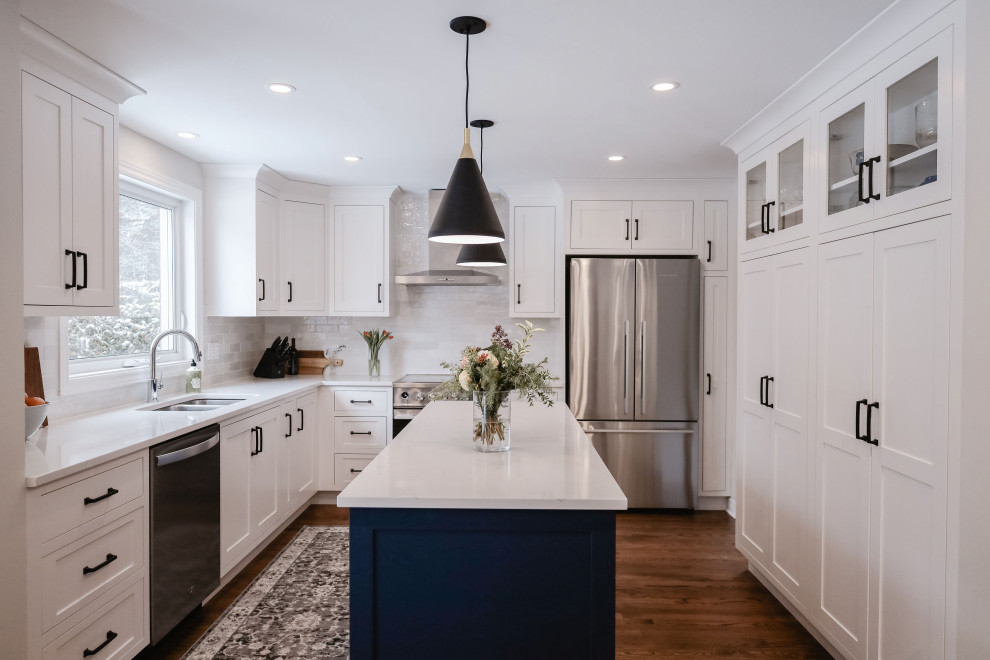Eat-in kitchen - small transitional u-shaped medium tone wood floor and brown floor eat-in kitchen idea in Ottawa with an undermount sink, shaker cabinets, white cabinets, quartz countertops, white backsplash, subway tile backsplash, stainless steel appliances, an island and white countertops