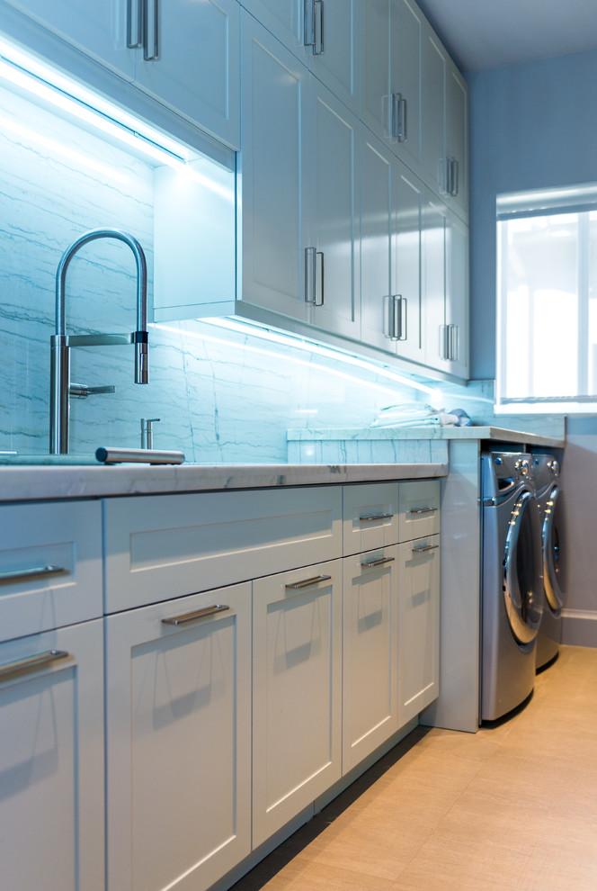 Photo of a large contemporary single-wall dedicated laundry room in Miami with shaker cabinets, white cabinets, an undermount sink, marble benchtops, blue walls, a side-by-side washer and dryer and light hardwood floors.