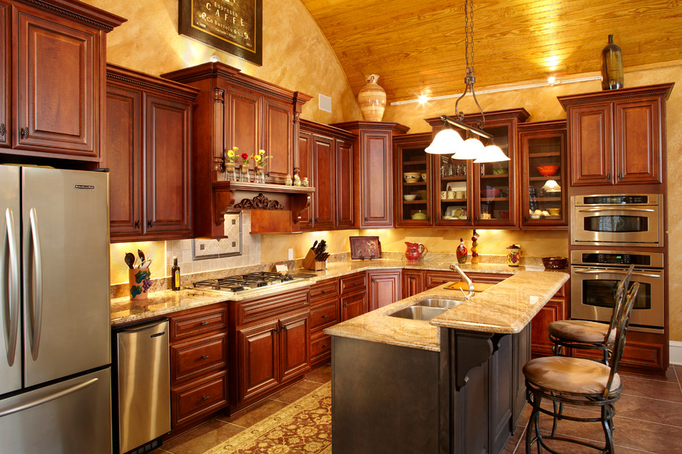Mid-sized transitional l-shaped travertine floor and brown floor open concept kitchen photo with raised-panel cabinets, dark wood cabinets, beige backsplash, stainless steel appliances, an island, a double-bowl sink, granite countertops and stone slab backsplash