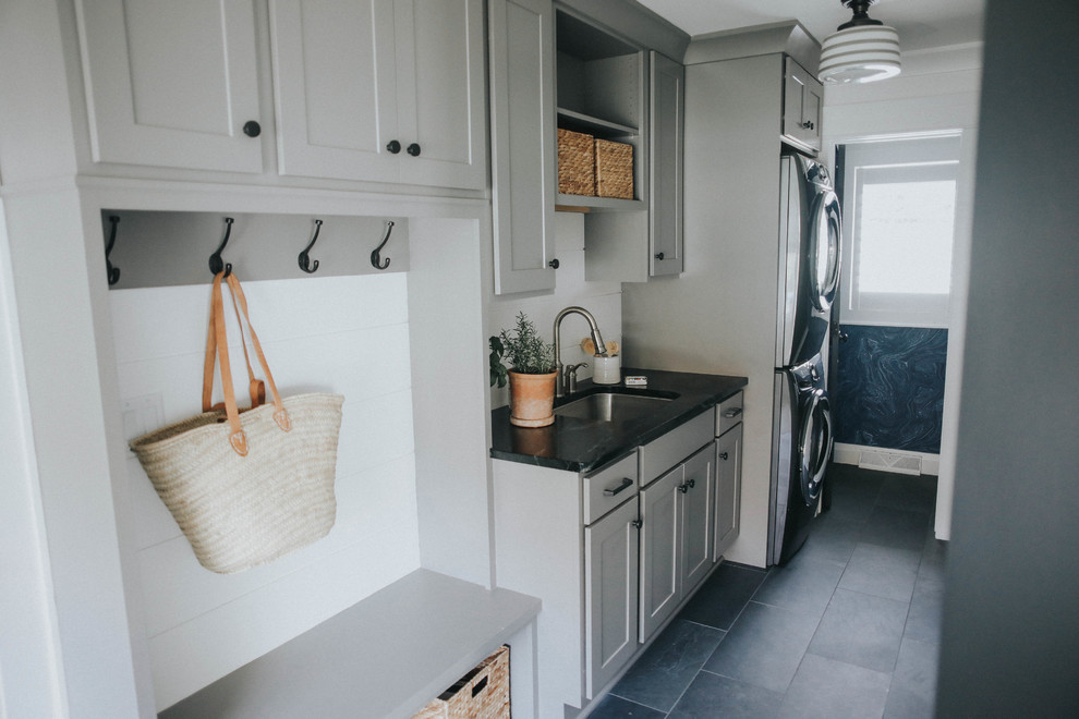 Photo of a mid-sized transitional single-wall dedicated laundry room in Burlington with shaker cabinets, grey cabinets, soapstone benchtops, white walls, slate floors and black floor.