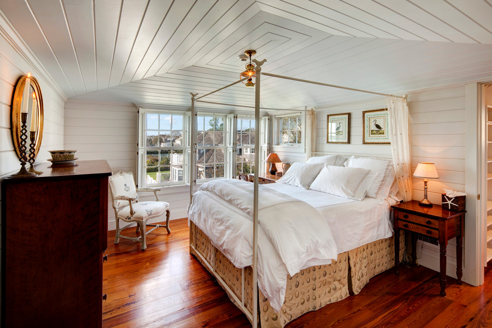 This is an example of a beach style bedroom in Boston with white walls, medium hardwood floors and no fireplace.