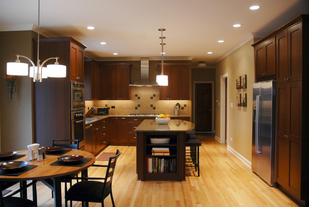 Example of a mid-sized transitional l-shaped light wood floor enclosed kitchen design in Chicago with an undermount sink, shaker cabinets, medium tone wood cabinets, quartz countertops, beige backsplash, porcelain backsplash, stainless steel appliances and an island