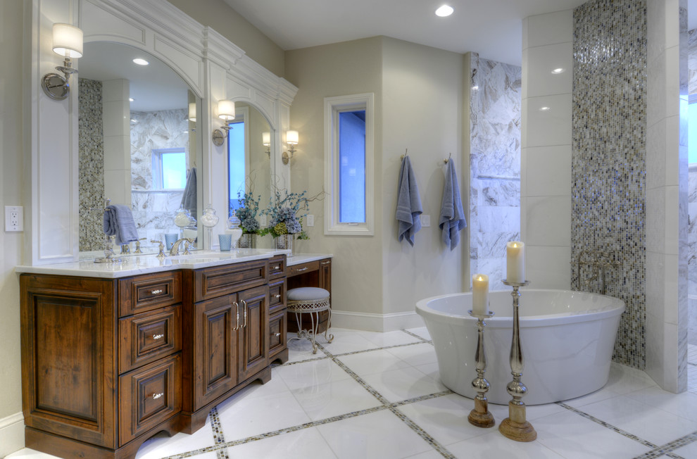 Photo of a large master bathroom in Denver with recessed-panel cabinets, distressed cabinets, a freestanding tub, an open shower, a one-piece toilet, white tile, ceramic tile, grey walls, marble floors, a drop-in sink and granite benchtops.