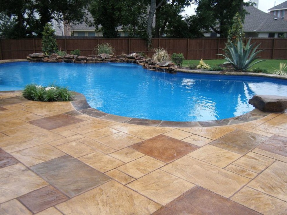 Example of a large transitional backyard custom-shaped and stamped concrete pool fountain design in Dallas