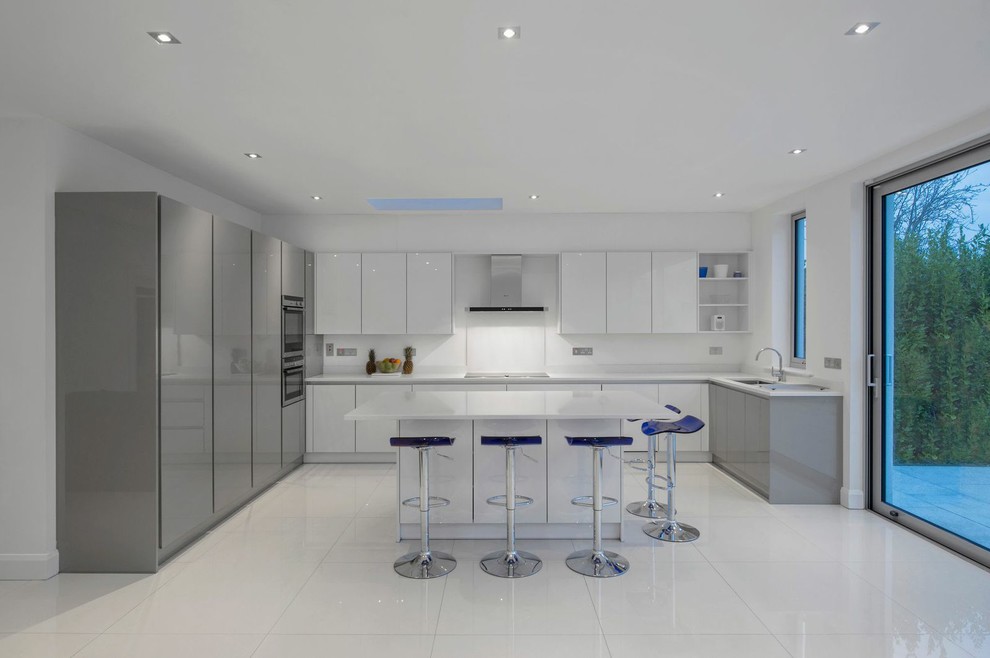 Mid-sized contemporary l-shaped eat-in kitchen in Dublin with an integrated sink, shaker cabinets, white cabinets, laminate benchtops, white splashback, panelled appliances, porcelain floors and a peninsula.