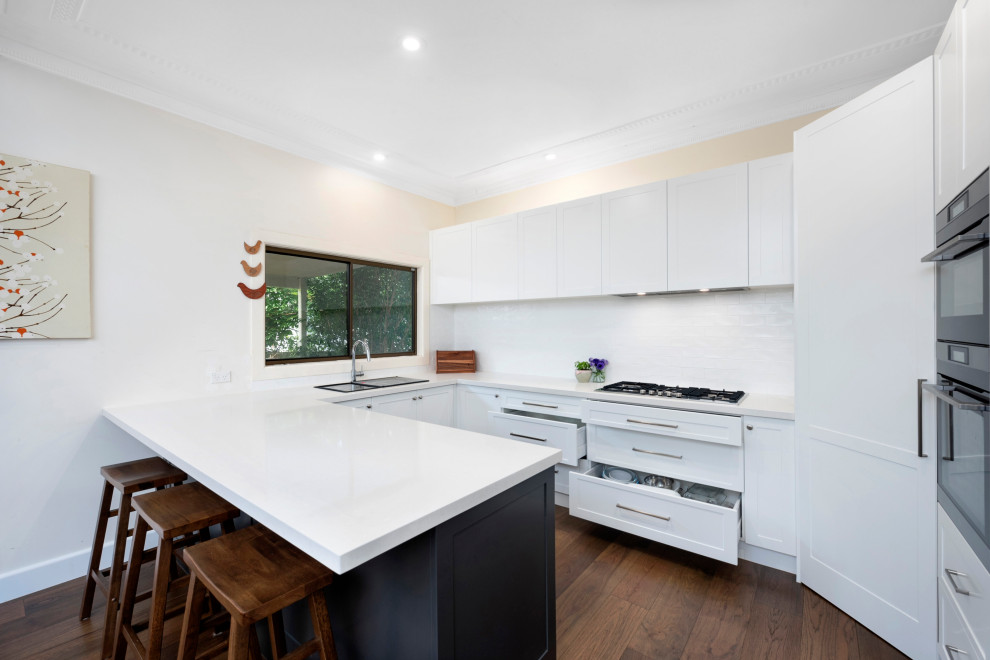 Mittelgroße Moderne Küche in U-Form mit Vorratsschrank, Schrankfronten im Shaker-Stil, weißen Schränken, Küchenrückwand in Weiß, Rückwand aus Keramikfliesen, Halbinsel und weißer Arbeitsplatte in Sydney