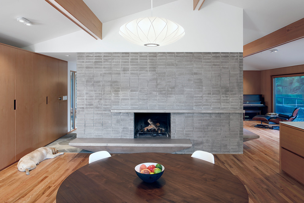 Mid-sized midcentury open plan dining in Seattle with brown walls, light hardwood floors, a standard fireplace and a stone fireplace surround.