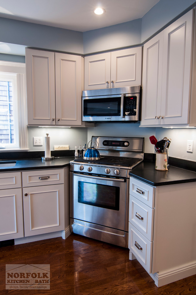 Open concept kitchen - transitional l-shaped medium tone wood floor open concept kitchen idea in Boston with a single-bowl sink, recessed-panel cabinets, white cabinets, granite countertops, stainless steel appliances and an island