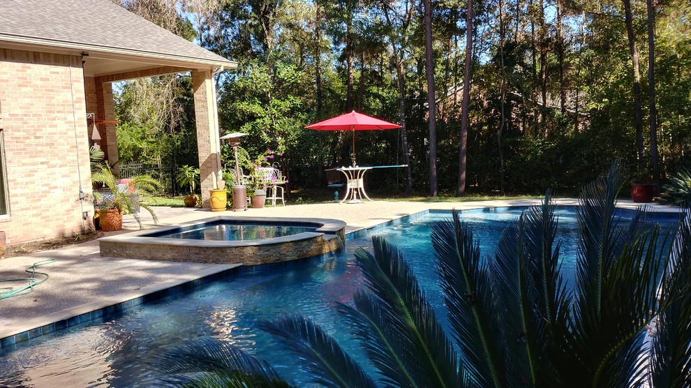 Photo of a mid-sized mediterranean backyard rectangular natural pool in Houston with a hot tub and concrete slab.