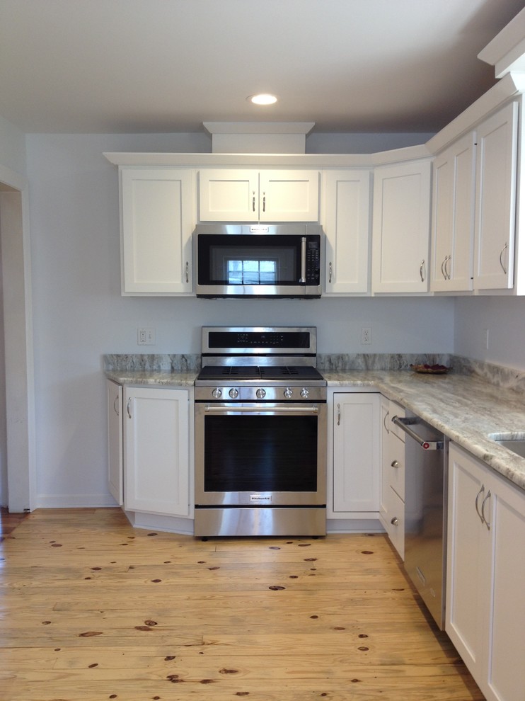 Inspiration for a mid-sized transitional l-shaped light wood floor enclosed kitchen remodel with an undermount sink, shaker cabinets, white cabinets, granite countertops, stainless steel appliances and no island