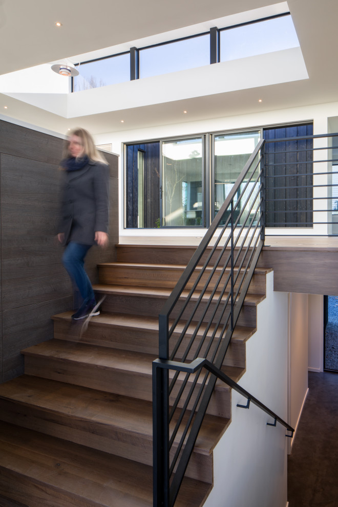 This is an example of a contemporary wood u-shaped metal railing staircase in Seattle with wood risers.