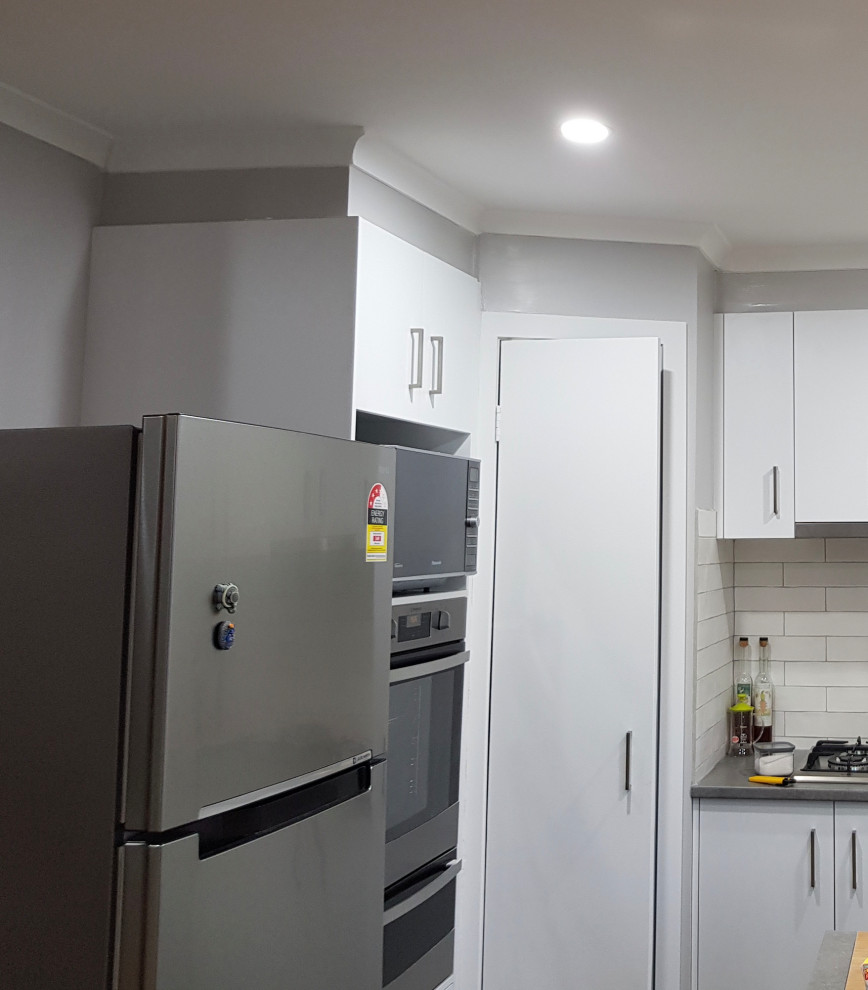 Inspiration for a small scandinavian u-shaped separate kitchen in Melbourne with a double-bowl sink, flat-panel cabinets, grey cabinets, laminate benchtops, white splashback, subway tile splashback, stainless steel appliances, porcelain floors, a peninsula, grey floor and grey benchtop.