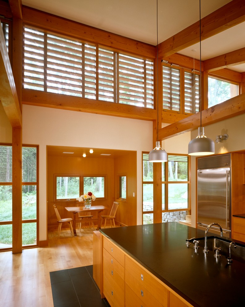 Open concept kitchen - large modern u-shaped slate floor open concept kitchen idea in Portland Maine with an undermount sink, flat-panel cabinets, medium tone wood cabinets, granite countertops, black backsplash, stone slab backsplash, stainless steel appliances, white walls and an island