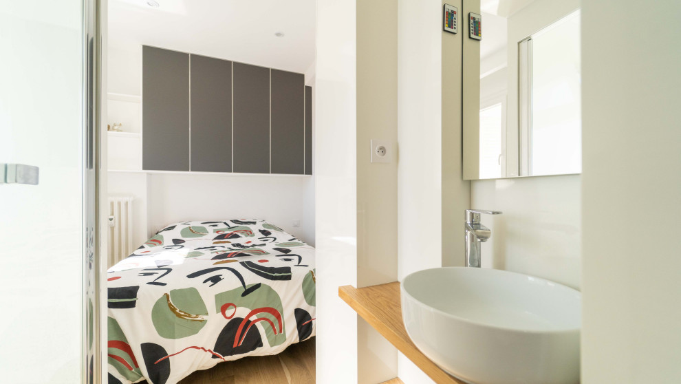 Immagine di una piccola camera da letto minimal con pareti bianche, parquet chiaro e soffitto ribassato