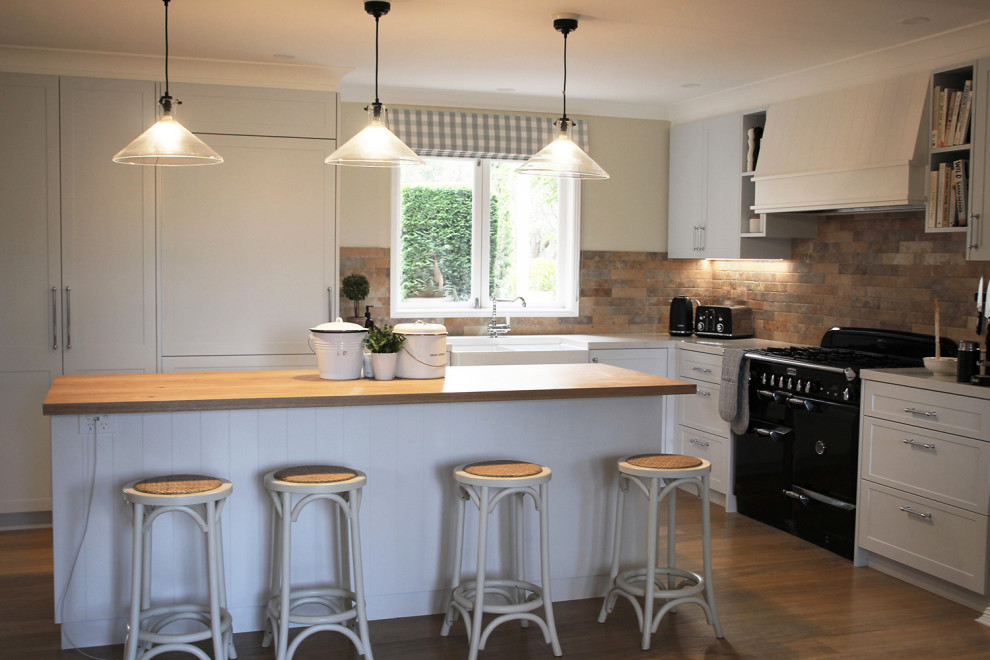 Inspiration for an expansive country kitchen in Other with a farmhouse sink, shaker cabinets, blue cabinets, quartz benchtops, multi-coloured splashback, subway tile splashback, medium hardwood floors, with island, brown floor and white benchtop.