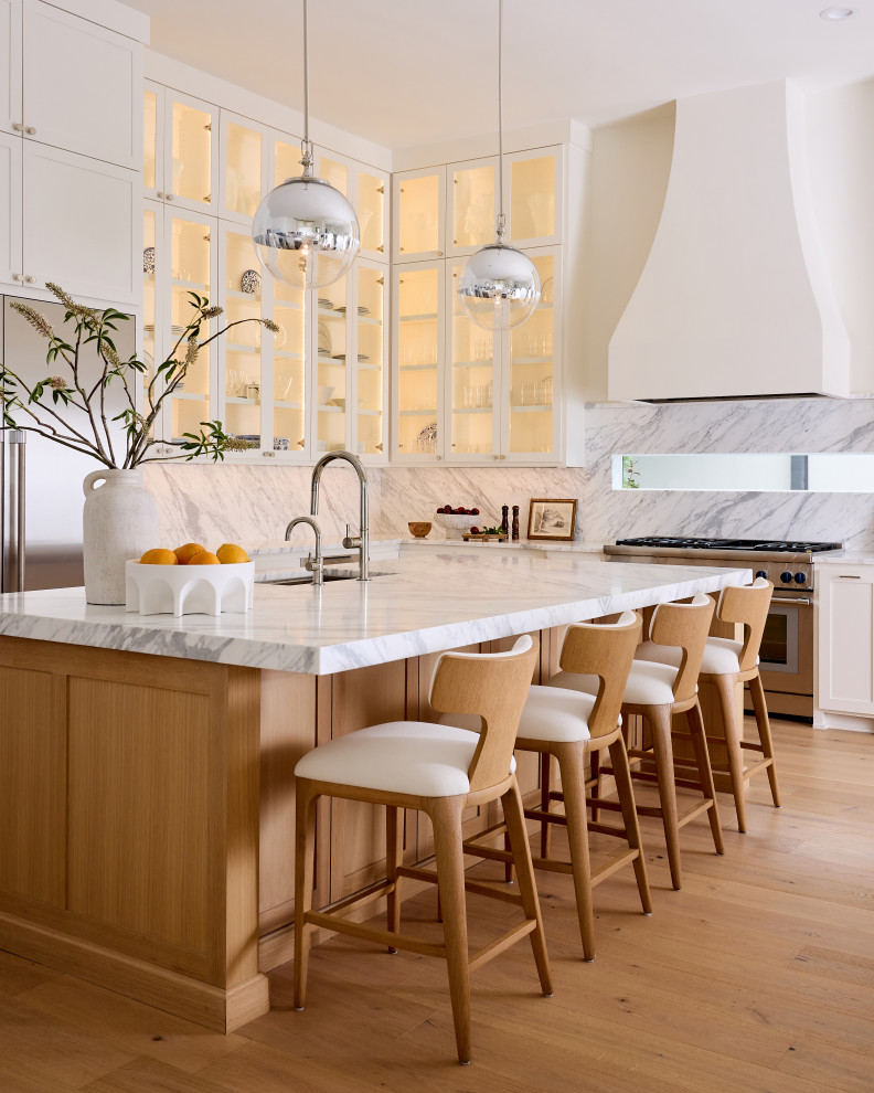 Transitional l-shaped light wood floor open concept kitchen photo in Dallas with shaker cabinets, marble countertops, white backsplash, marble backsplash, stainless steel appliances, an island and white countertops