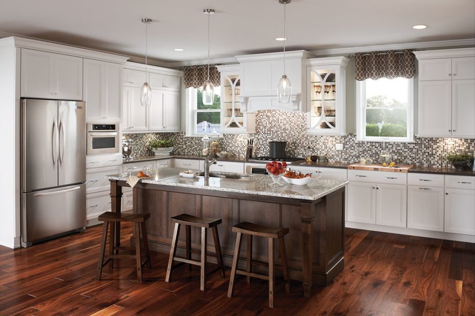 Design ideas for a mid-sized traditional single-wall kitchen in New Orleans with an undermount sink, recessed-panel cabinets, white cabinets, solid surface benchtops, multi-coloured splashback, mosaic tile splashback, stainless steel appliances, medium hardwood floors and with island.