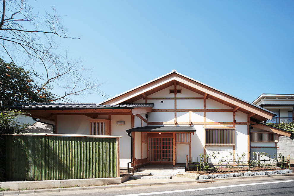 Asian white exterior in Tokyo with a gable roof and a tile roof.