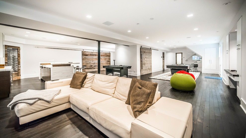 Photo of a large modern look-out basement in New York with white walls, dark hardwood floors, a standard fireplace and a tile fireplace surround.