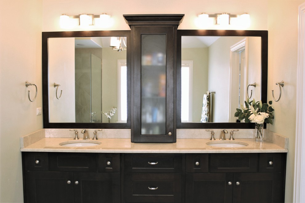 This is an example of a mid-sized transitional master bathroom in Chicago with shaker cabinets, an undermount sink, dark wood cabinets, a corner shower, beige walls, marble benchtops and a hinged shower door.