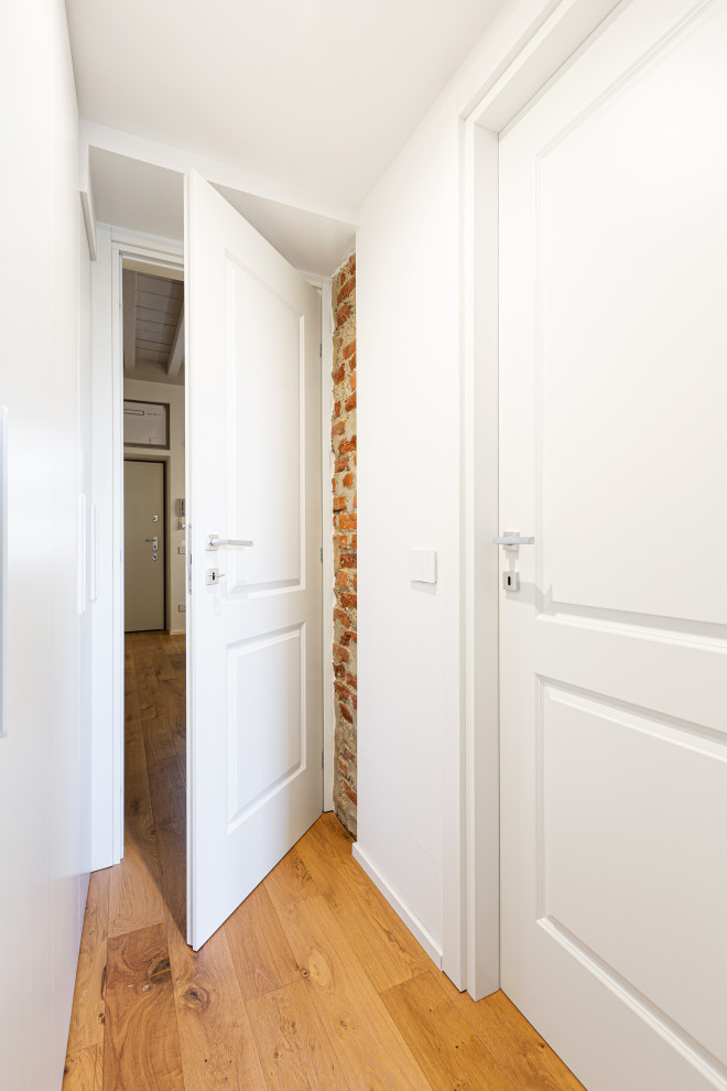 Idee per un piccolo ingresso o corridoio scandinavo con pareti bianche, parquet chiaro, pavimento marrone e soffitto in legno